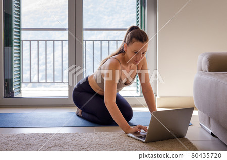 Young woman taking online fitness class at home Young woman taking online fitness class at home 80435720