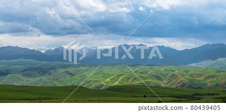 Grassland and mountains in a cloudy day. Photo in Kalajun grassland in Xinjiang, China. Grassland and mountains in a cloudy day. Photo in Kalajun grassland in Xinjiang, China. 80439405