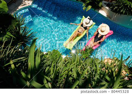 Women Relaxing on Floating Mattresses Women Relaxing on Floating Mattresses 80445328