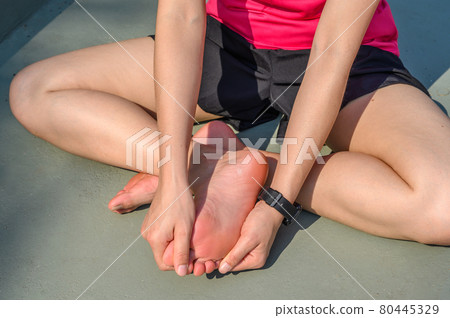 Cropped view of runner woman suffering from injury and she trying to do foot massage by herself. A foot massage used to decrease pain, relieve tension and improve circulation. Cropped view of runner woman suffering from injury and she trying to do foot massage by herself. A foot massage used to decrease pain, relieve tension and improve circulation. 80445329