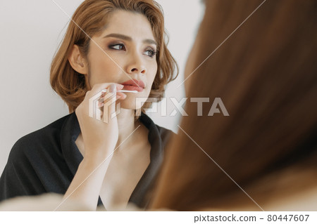 Woman makeup artist is at work and wearing makeup on her model. Woman makeup artist is at work and wearing makeup on her model. 80447607