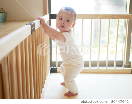 一個抓住並站在嬰兒圍欄中的半嬰兒 80447641