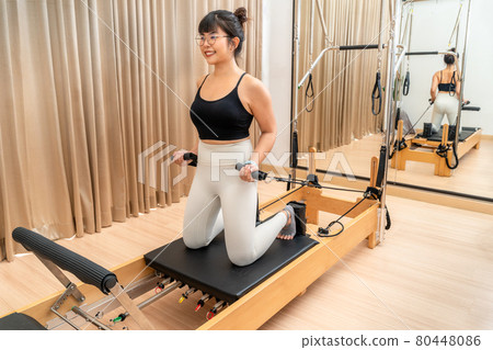 Young Asian woman working on pilates reformer machine during her health exercise 80448086