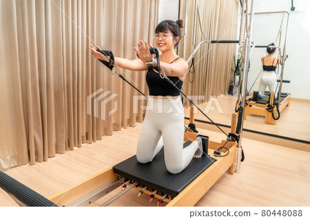 Young Asian woman working on pilates reformer machine during her health exercise 80448088