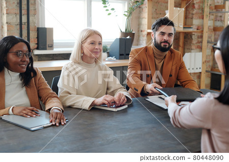Young bearded businessman passing folder with contract to applicant Young bearded businessman passing folder with contract to applicant 80448090