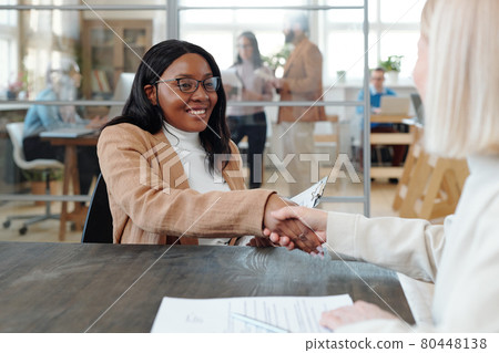 Cheerful African female specialist shaking hand of new employer after interview 80448138