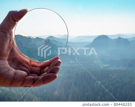 Crystal glass ball in a man's hand. The morning misty hilly landscape Crystal glass ball in a man's hand. The morning misty hilly landscape 80448283