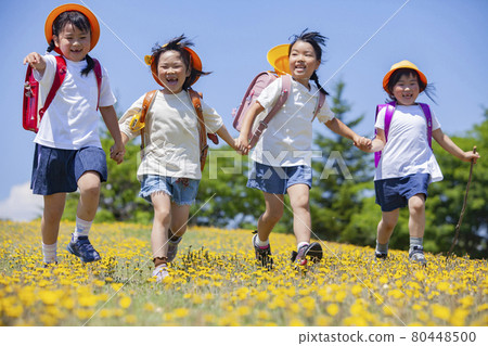 Elementary school student carrying a school bag walking in a flower field 80448500