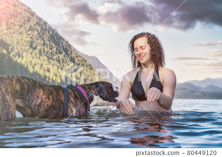 Caucasian Woman swimming in a lake with dog 80449120