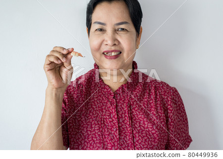 Senior asian woman is holding dentures in hands,Dental prosthesis,False teeth,Close up 80449936