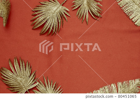 Decorative golden leaves on red textile backdrop 80451065