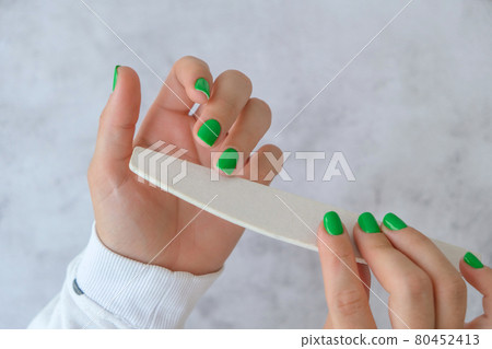 Manicured female hands with stylish green nails. Trendy modern design manicure. Gel nails. Skin care. Beauty treatment. Nail care. Trendy colors. Manicure tools 80452413