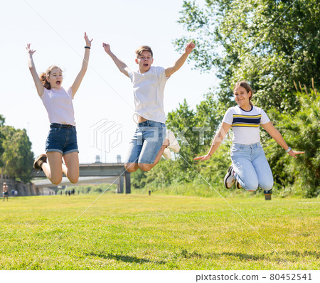 Teenagers jumping on green lawn in summertime 80452541