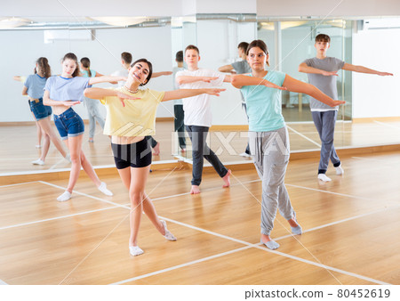 Diligent friendly smiling teenagers learn dance movements 80452619