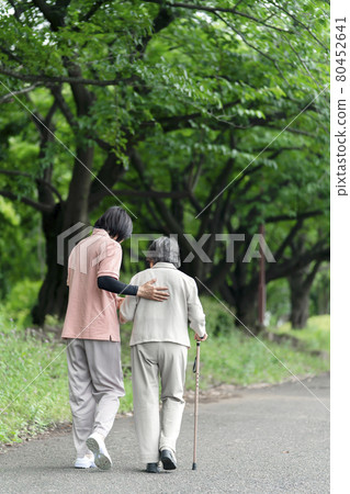 老年婦女在公園散步，後面有照顧者 80452641