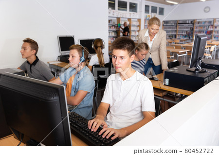 Pupils using computers at lesson, teacher teaching them Pupils using computers at lesson, teacher teaching them 80452722