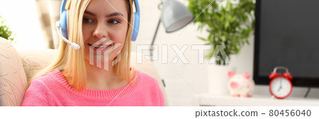 young beautiful blond woman sit on the sofa in livingroom hold binder in arms work with laptop listen to music 80456040