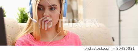 young beautiful blond woman sit on the sofa in livingroom hold binder in arms work with laptop listen to music 80456051