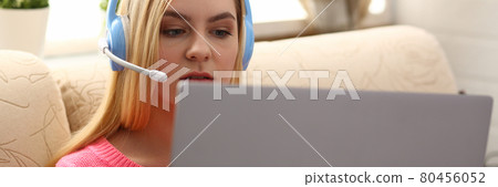 young beautiful blond woman sit on the sofa in livingroom hold laptop in arms listen to music 80456052