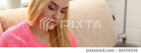 young beautiful blond woman sit on the sofa in livingroom hold binder in arms 80456056