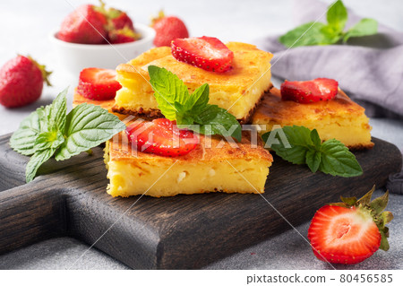Cottage cheese casserole with strawberries and mint. Delicious homemade dessert made of curd and fresh berries with cream. Gray concrete background close up. Cottage cheese casserole with strawberries and mint. Delicious homemade dessert made of curd and fresh berries with cream. Gray concrete background close up. 80456585