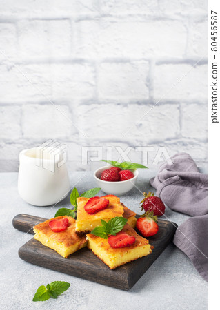 Cottage cheese casserole with strawberries and mint. Delicious homemade dessert made of curd and fresh berries with cream. Gray concrete background, copy space. 80456587