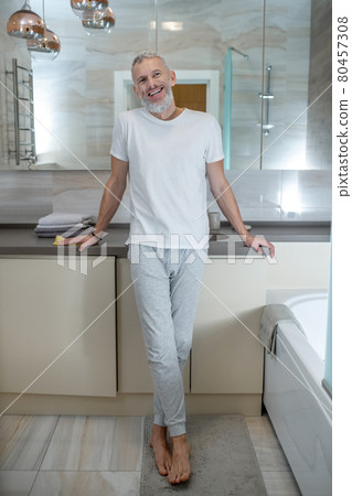 A tall mature amn standing in a bathroom and looking positive 80457308