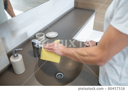 A man in a white tshirt doing some housework and cleaning 80457316