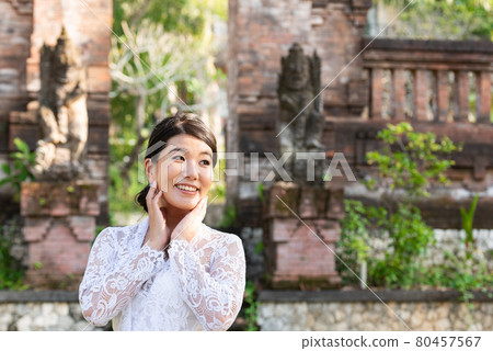 A woman in a traditional costume (Kebaya) at a traditional temple in Bali A woman in a traditional costume (Kebaya) at a traditional temple in Bali 80457567