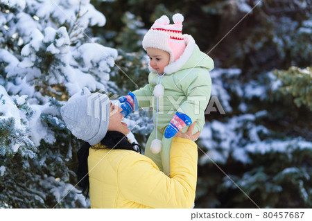 family portrait in the winter forest, mother and child looks on snow, bright sunlight and shadows on the snow, beautiful nature family portrait in the winter forest, mother and child looks on snow, bright sunlight and shadows on the snow, beautiful nature 80457687