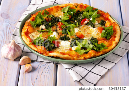 Pizza with with spinach, mozzarella, cherry tomatoes and garlic. 80458187