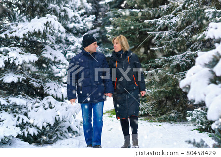 couple walking in a winter forest, two adult people, man and woman, beautiful nature with bright snowy fir trees couple walking in a winter forest, two adult people, man and woman, beautiful nature with bright snowy fir trees 80458429
