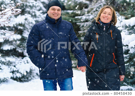 couple walking in a winter forest, two adult people, man and woman, beautiful nature with bright snowy fir trees 80458430