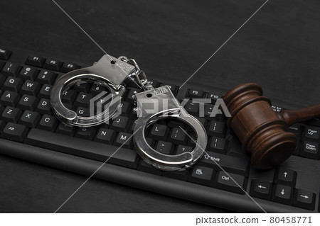 Judge gavel and handcuffs on computer keyboard. Cyber crime . Legal liability on the Internet. Online piracy. Judge gavel and handcuffs on computer keyboard. Cyber crime . Legal liability on the Internet. Online piracy. 80458771