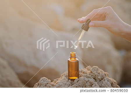 close up of woman hand hold dropping dosing a biological and ecological hemp plant herbal pharmaceutical cbd oil from a jar. On natural stone background. 80459030