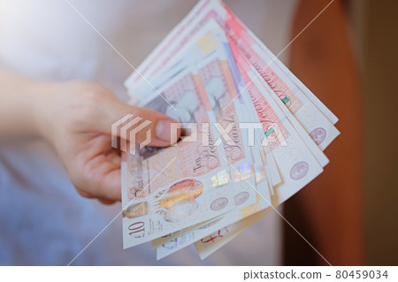 New Plastic Ten and twenty Pound note sterling in woman hands. Crisis and saving concept. British finance sistem New Plastic Ten and twenty Pound note sterling in woman hands. Crisis and saving concept. British finance sistem 80459034