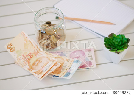 Notebooks, money jars with coins and summary report with bar charts and circles placed on a white wooden table. Stock Analysis and Savings concept. . Turkish currency liras . Notebooks, money jars with coins and summary report with bar charts and circles placed on a white wooden table. Stock Analysis and Savings concept. . Turkish currency liras . 80459272