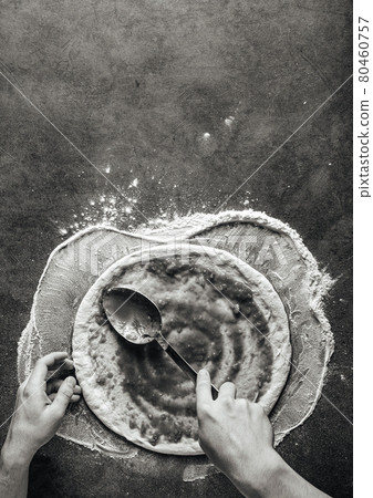 Making a pizza spreding tomato sauce on the dough Making a pizza spreding tomato sauce on the dough 80460757