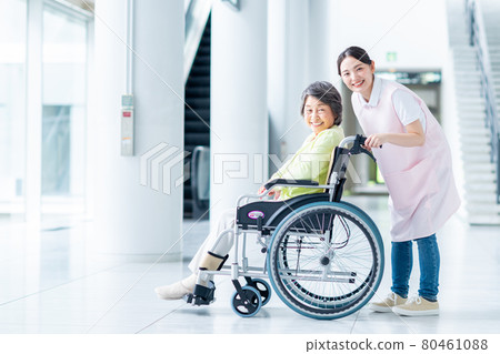 Elderly people in wheelchairs and young women in long-term care staff Elderly people in wheelchairs and young women in long-term care staff 80461088