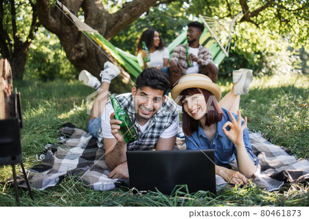 Positive diverse friends using laptop at green garden 80461873