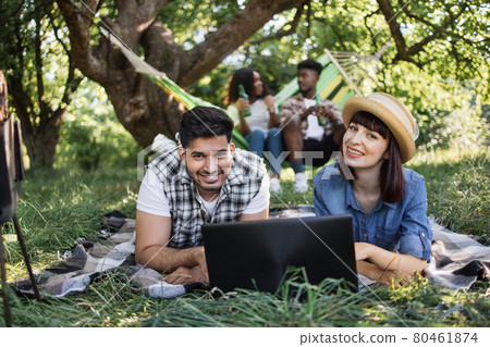 Four diverse friends using laptop on picnic at garden Four diverse friends using laptop on picnic at garden 80461874