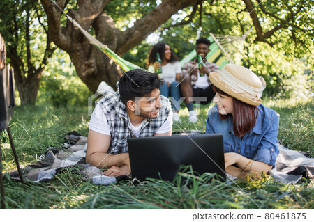 Multiracial friends with laptop relaxing at garden Multiracial friends with laptop relaxing at garden 80461875