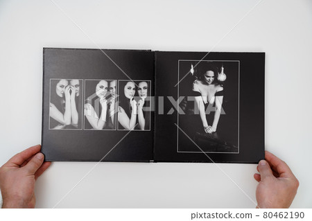 hands holding a open photobook from photo shoot of an woman on white background. hands holding a open photobook from photo shoot of an woman on white background. 80462190