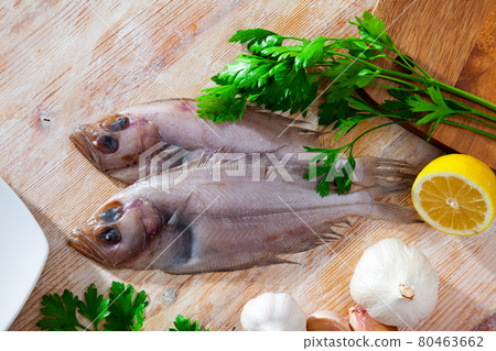 Gallo pescado on cutting board with lemon and parsley. Gallo pescado on cutting board with lemon and parsley. 80463662