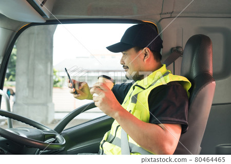Cheerful men truck driver holding a cup of coffee Cheerful men truck driver holding a cup of coffee 80464465