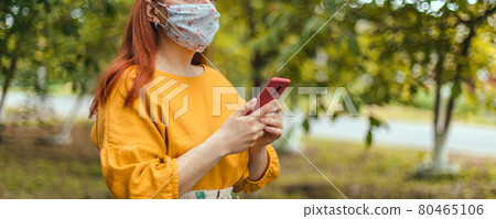 COVID-19 Coronavirus Young woman wearing medical mask uses smartphone app in city park during pandemic COVID-19 Coronavirus Young woman wearing medical mask uses smartphone app in city park during pandemic 80465106