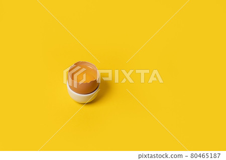 One brown chicken egg in egg cup on yellow background, negative space. One brown chicken egg in egg cup on yellow background, negative space. 80465187