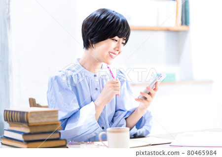 一位年輕女子在客廳學習時使用智能手機 一位年輕女子在客廳學習時使用智能手機 80465984