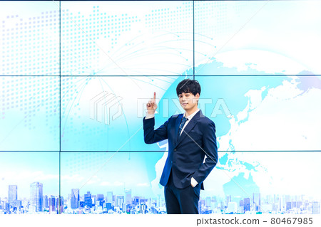 A businessman standing in front of a large display 80467985