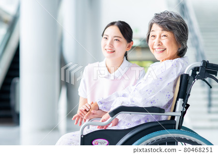 Elderly and caregiving young woman in wheelchair 80468251